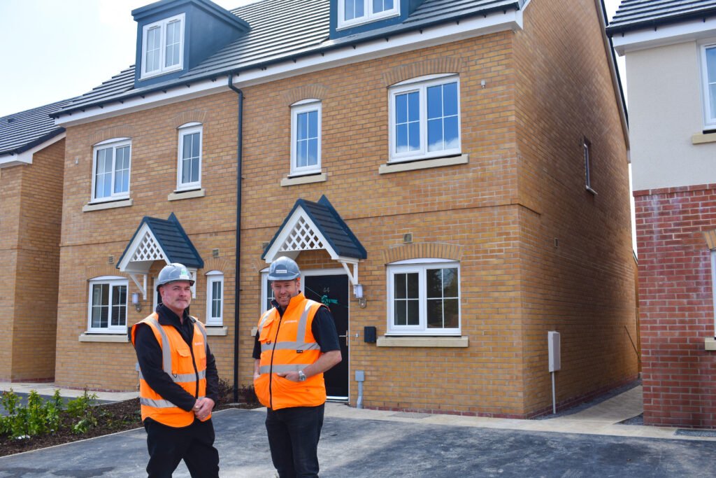 Two men in hi-vis jackets standing in front of Bromford's newly finished homes in Cheltenham