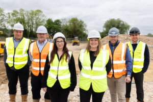 Six Bromford colleagues in high vis jackets and hard hats at its latest development site in Gloucester